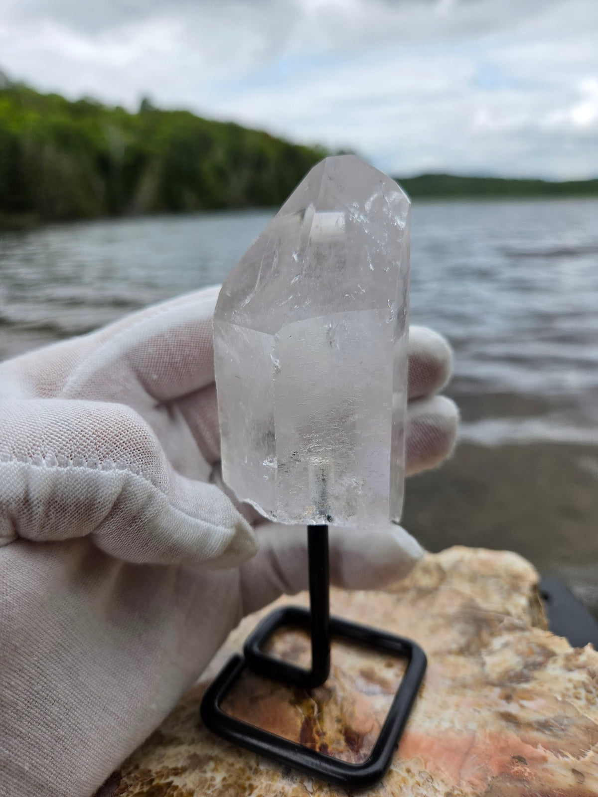 Clear quartz crystal on stand angled view