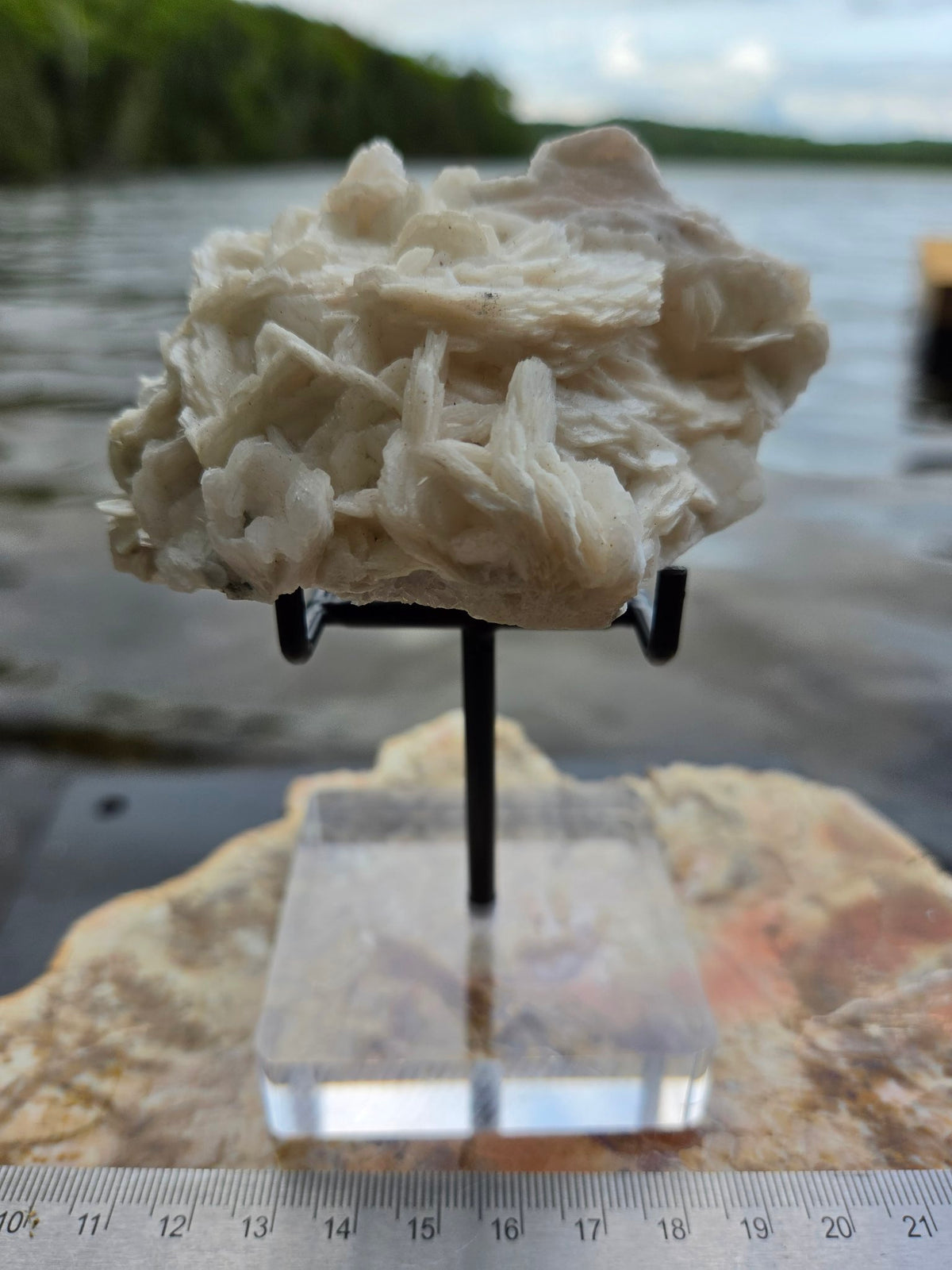 Pink calcite cluster on stand with ruler for scale
